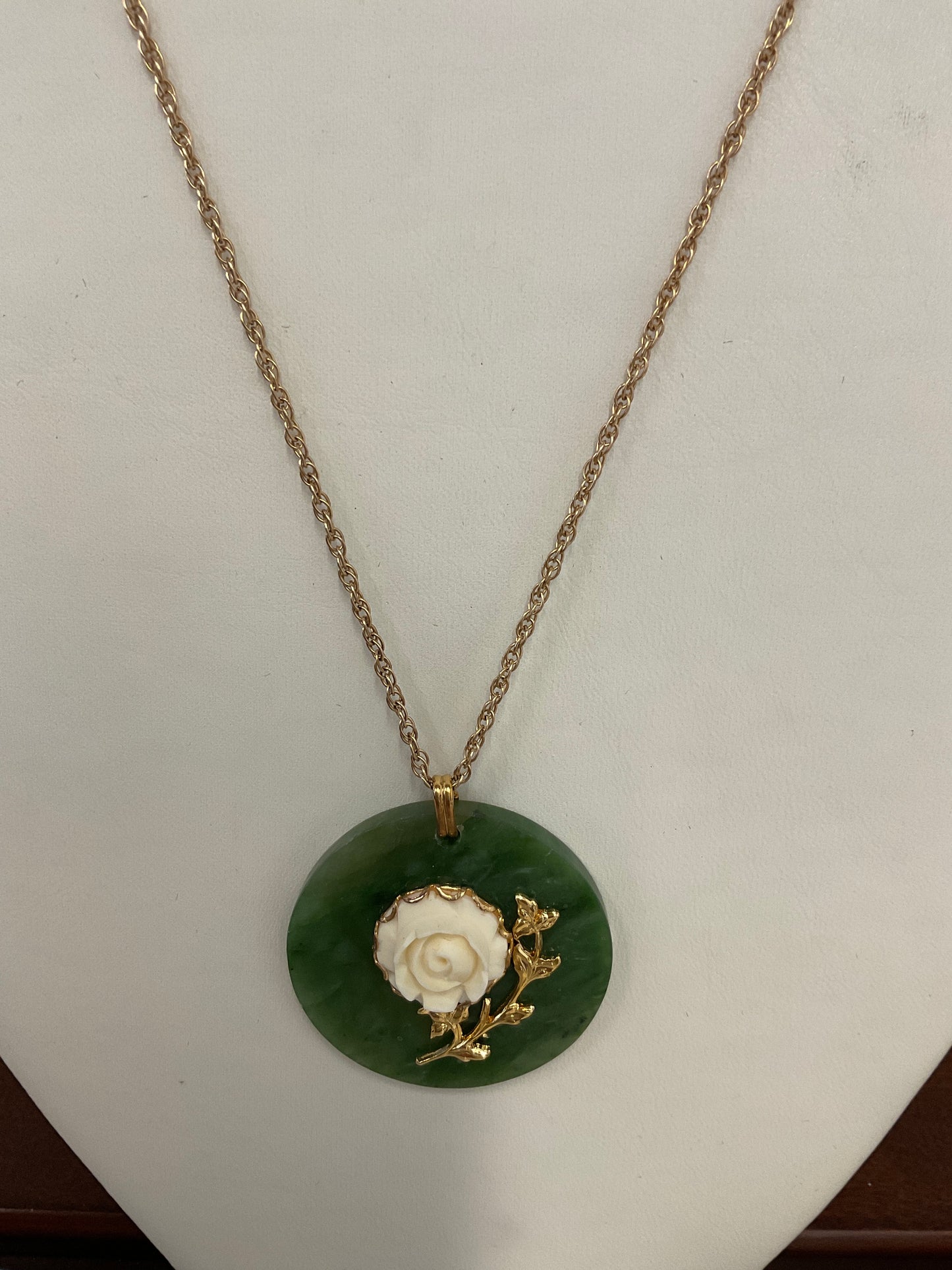 Jade pendant with floral design. Gold toned chain
