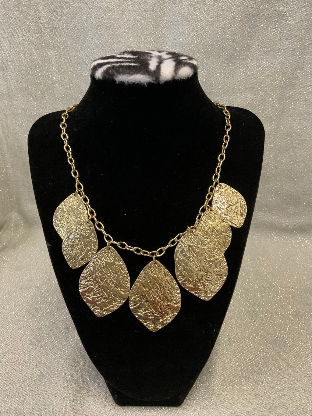 Gold toned fashion necklace with hammered leaf shaped pendants